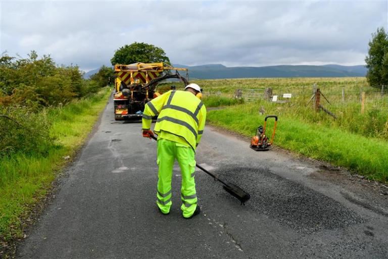 Highways employee working on a road wearing high-visibility clothing.