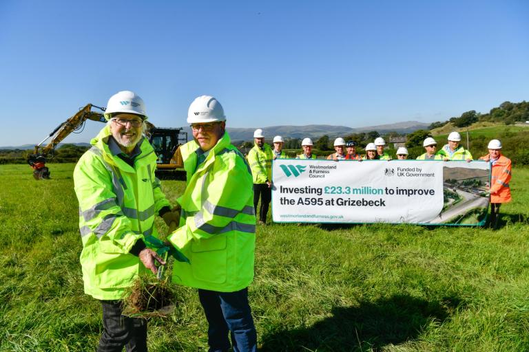 Photo of the team with a banner which details the £23.3 million investment to improve the A595 at Grizebeck